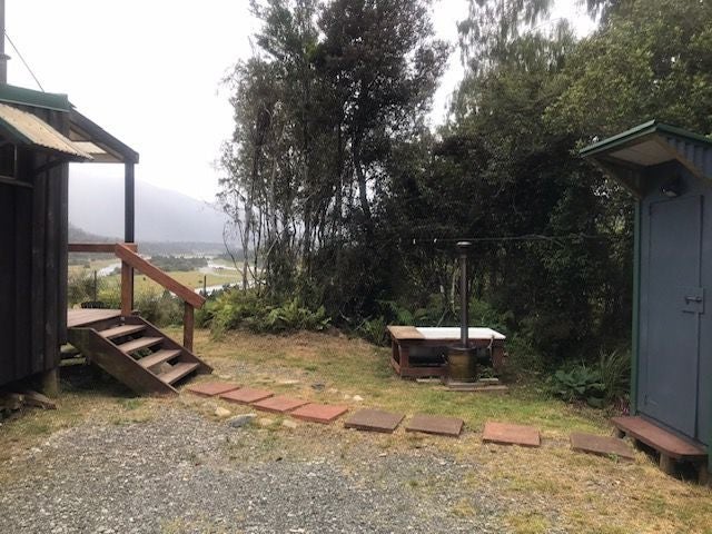 A small outdoor bathroom with a toilet and a shower.