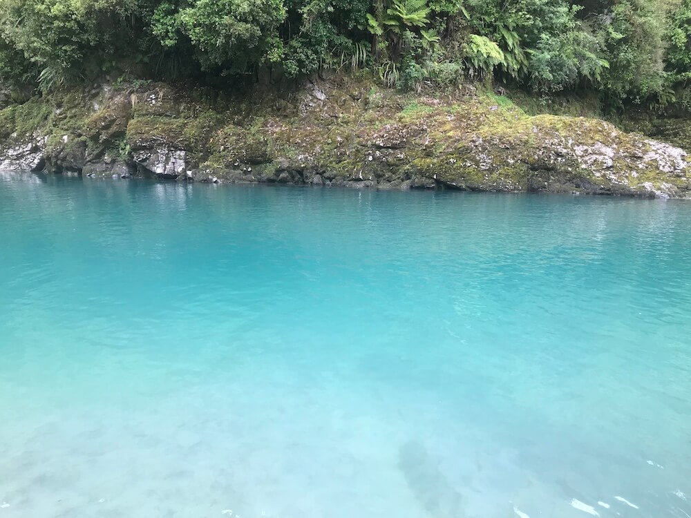 A blue lake with a lot of trees in the background.