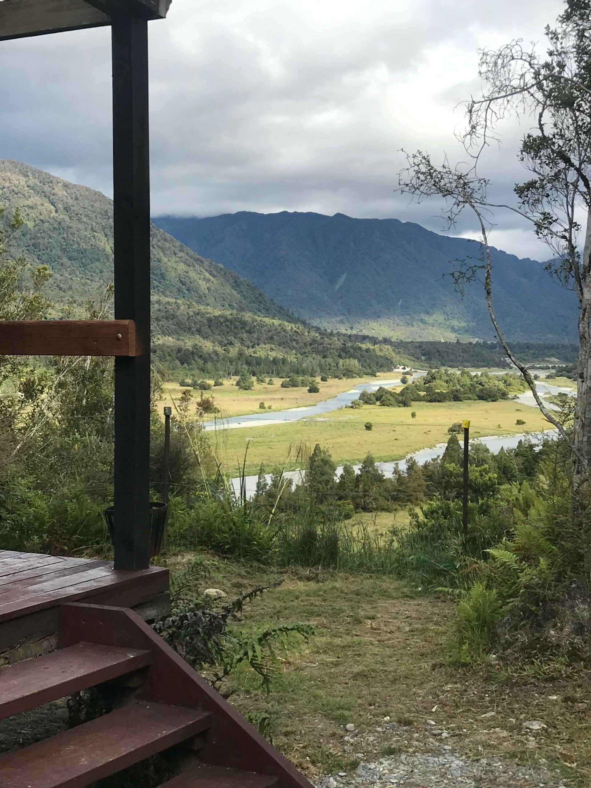 A cabin overlooking a river and mountains.