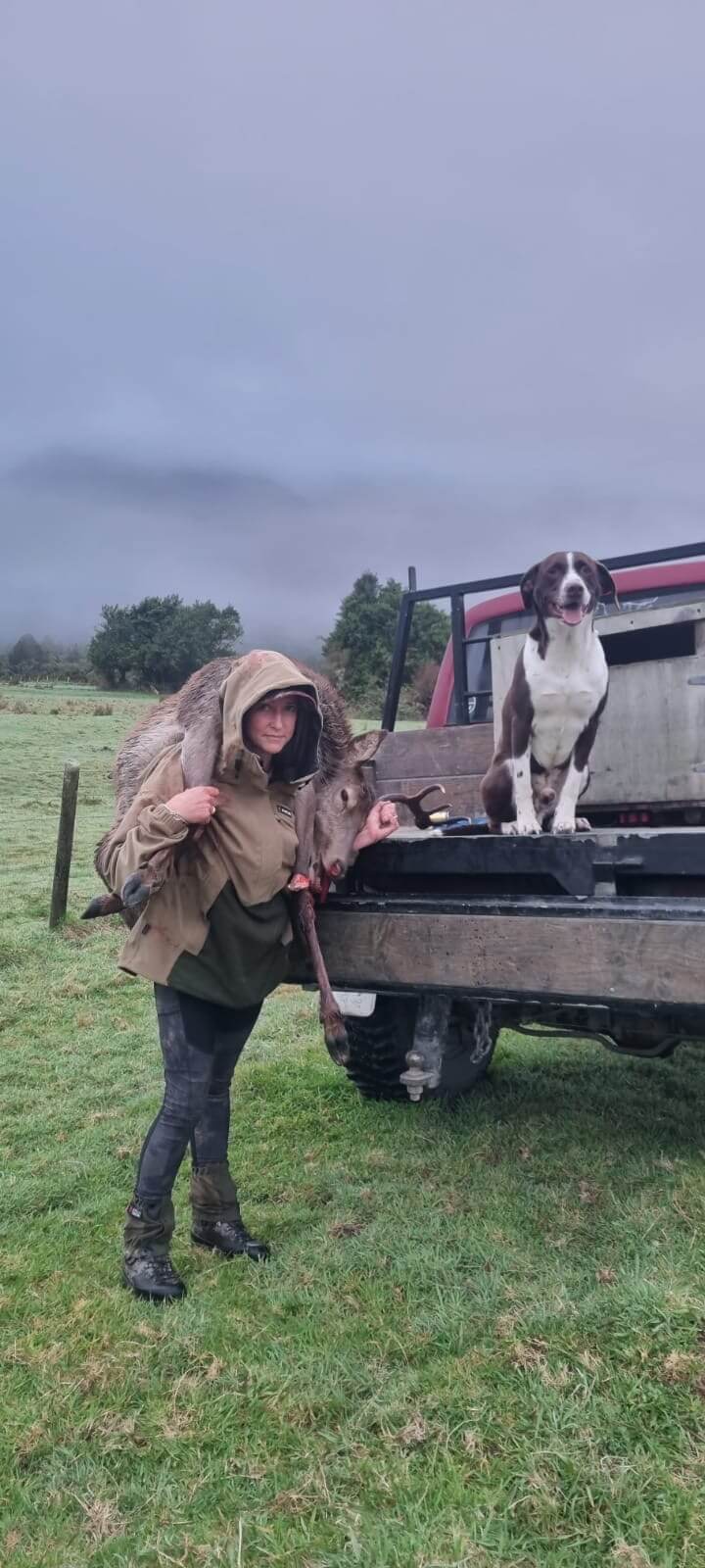 A man with a dog in the back of a pickup truck.